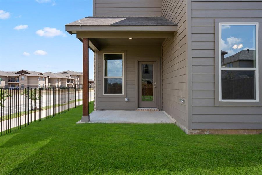 View of exterior entry featuring a patio and a yard