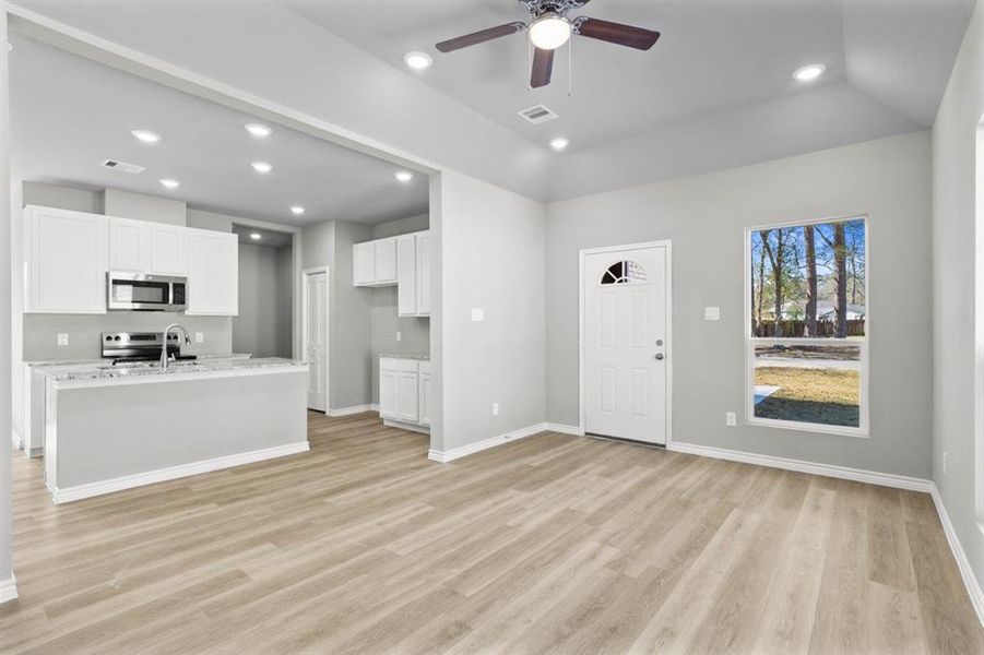 This view is showing the front door entry with the kitchen to the left, along with the entry to the garage, mud room and utility room. Notice the nice ceiling design in the living room.