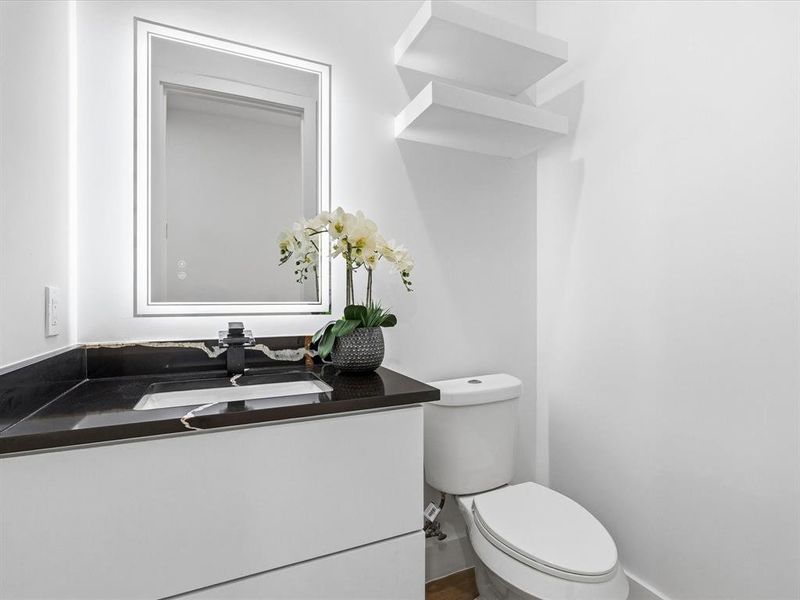 Modern bathroom featuring a floating vanity with a dark stone countertop, integrated sink, and matte black faucet