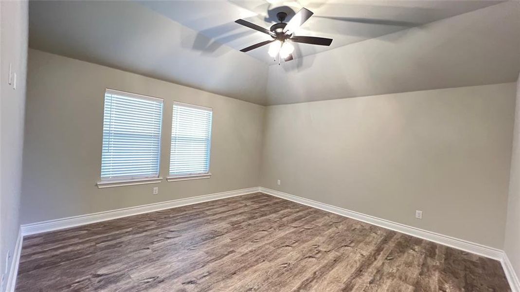 Empty room featuring lofted ceiling, ceiling fan, and hardwood / wood-style floors