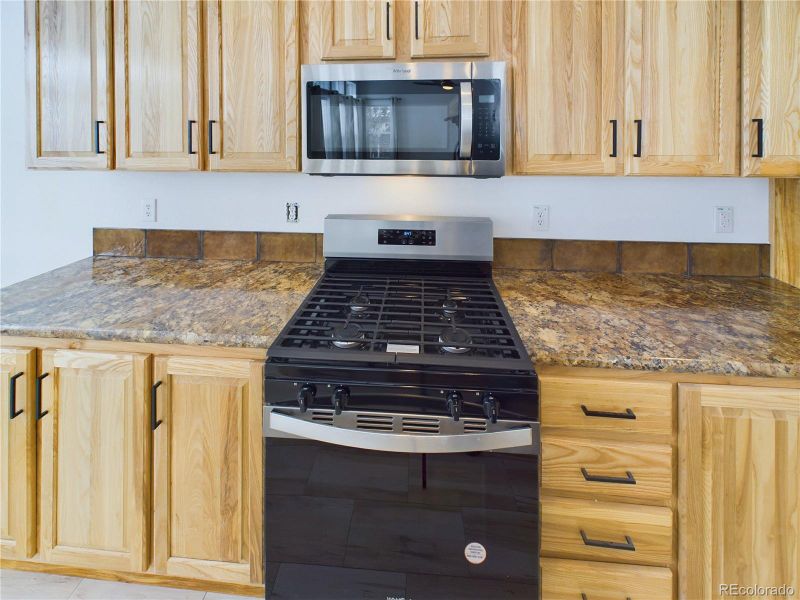 Kitchen with light maple cabinetry, range with gas stovetop