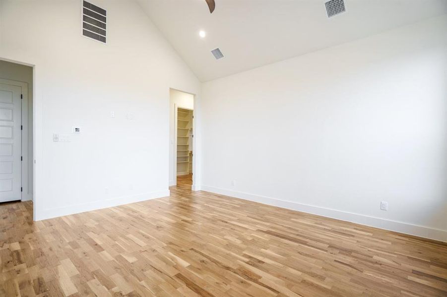 Empty room with light hardwood / wood-style floors and high vaulted ceiling