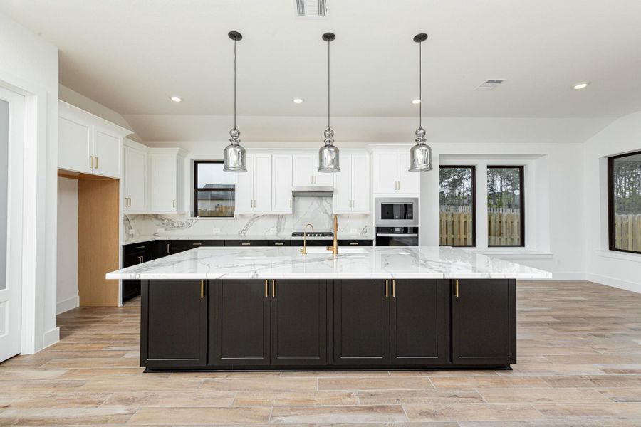 The stunning and generously sized center island features a breakfast bar, perfect for casual dining and entertaining. The island is beautifully designed with pristine quartz countertop and elegant pendant lights.