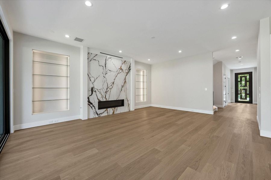 The expansive living room captivates with a statement fireplace framed by built-in, illuminated glass shelving — perfect for display. The expansive living room captivates with a statement fireplace framed by built-in, illuminated glass shelving — perfect for display.