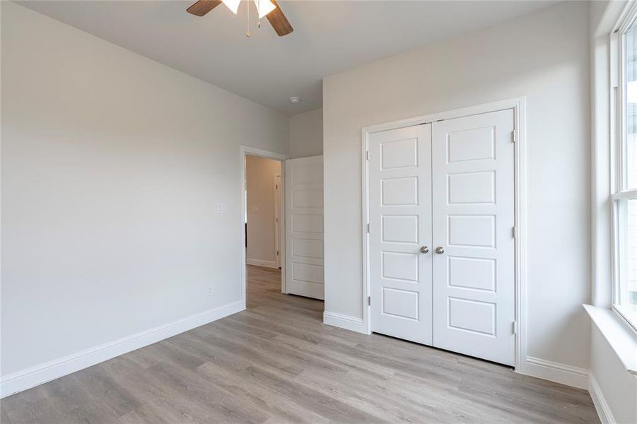 Unfurnished bedroom featuring light wood-type flooring, a closet, and ceiling fan