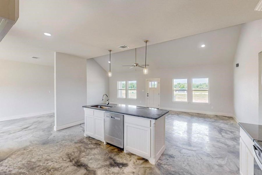 Kitchen featuring plenty of natural light, a center island with sink, white cabinetry, and stainless steel dishwasher