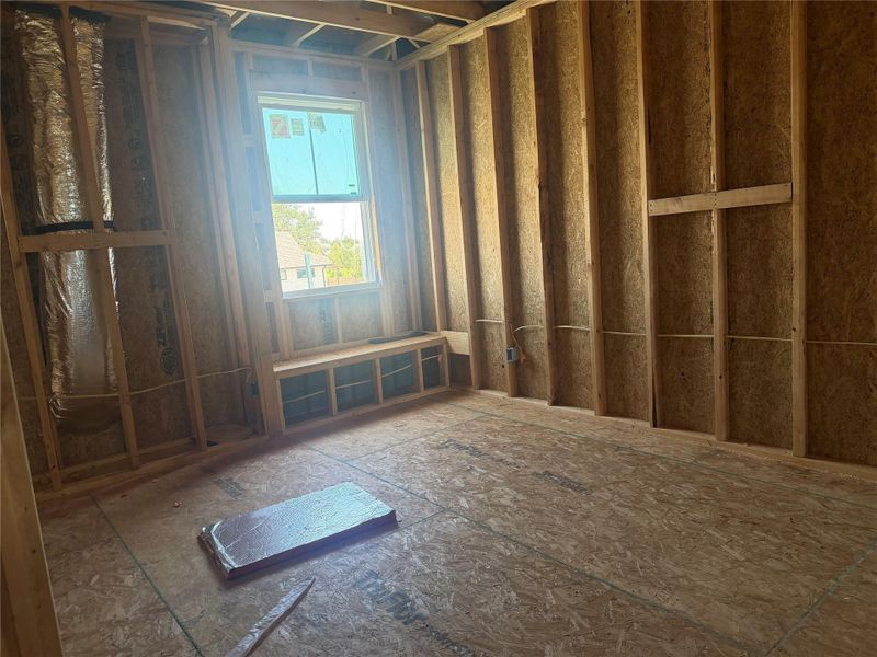 Exposed framing and subflooring outline a potential bedroom featuring a built-in window bench.