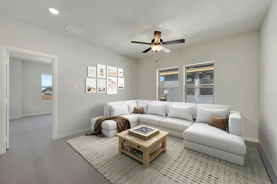 Carpeted living area with ceiling fan and recessed lighting