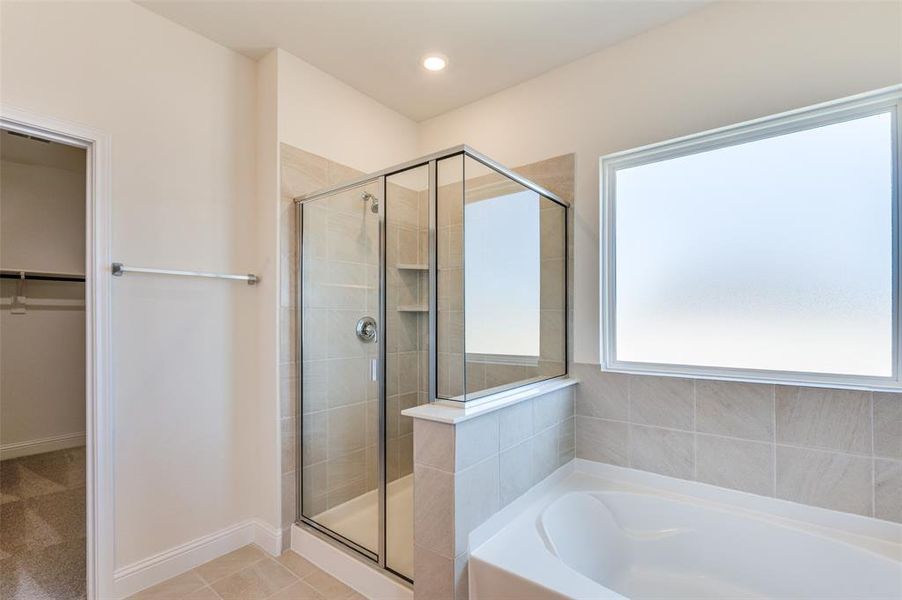 Full bathroom featuring a stall shower, a bath, a walk in closet, and tile patterned flooring