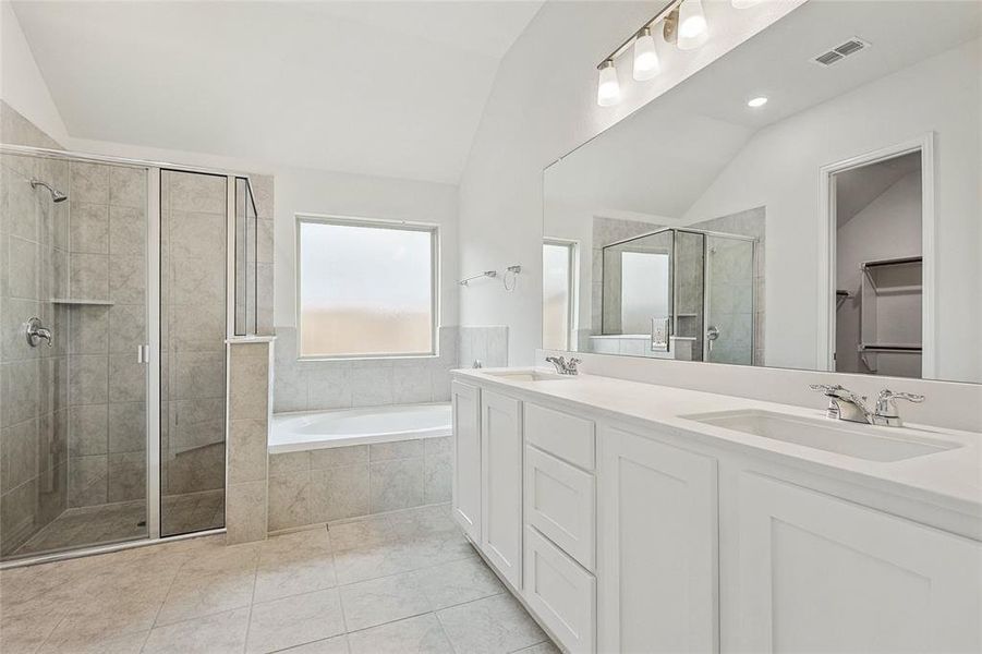 Bathroom featuring vaulted ceiling, separate shower and tub, double sink, and tile floors