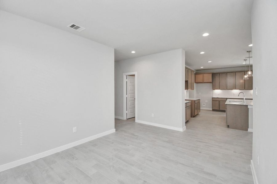 Create lasting memories with your family and friends at the dining table! This expansive dining room showcases sophisticated flooring, custom paint, and seamlessly connects to the family room and kitchen, providing an open and inviting atmosphere. Sample photo of completed home with similar floor plan. Actual colors and selections may vary.