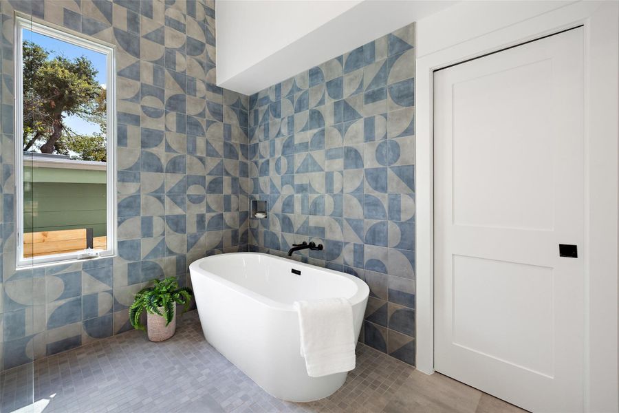 Full bathroom featuring tile walls, a freestanding tub, and tile patterned floors