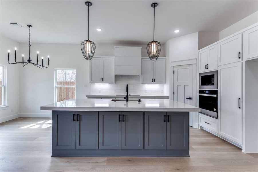 Kitchen with visible vents, white cabinets, stainless steel oven, a sink, and black microwave