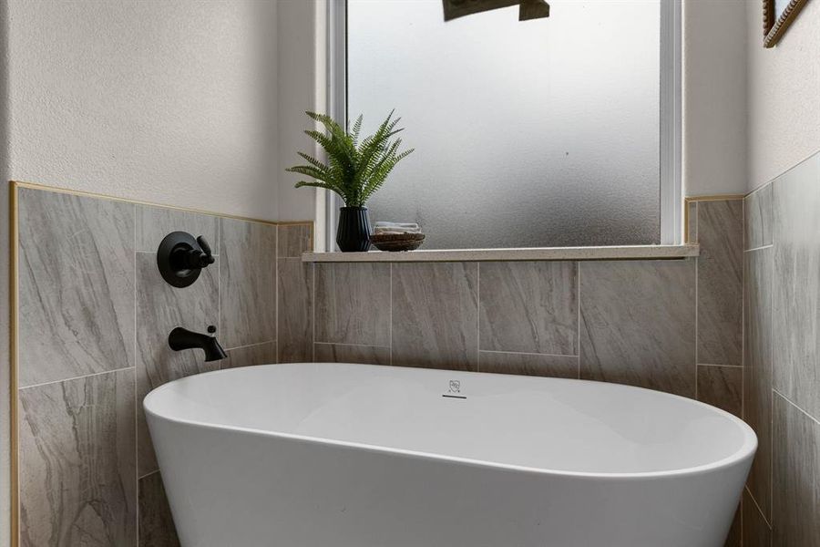 Bathroom with tile walls and a tub to relax in