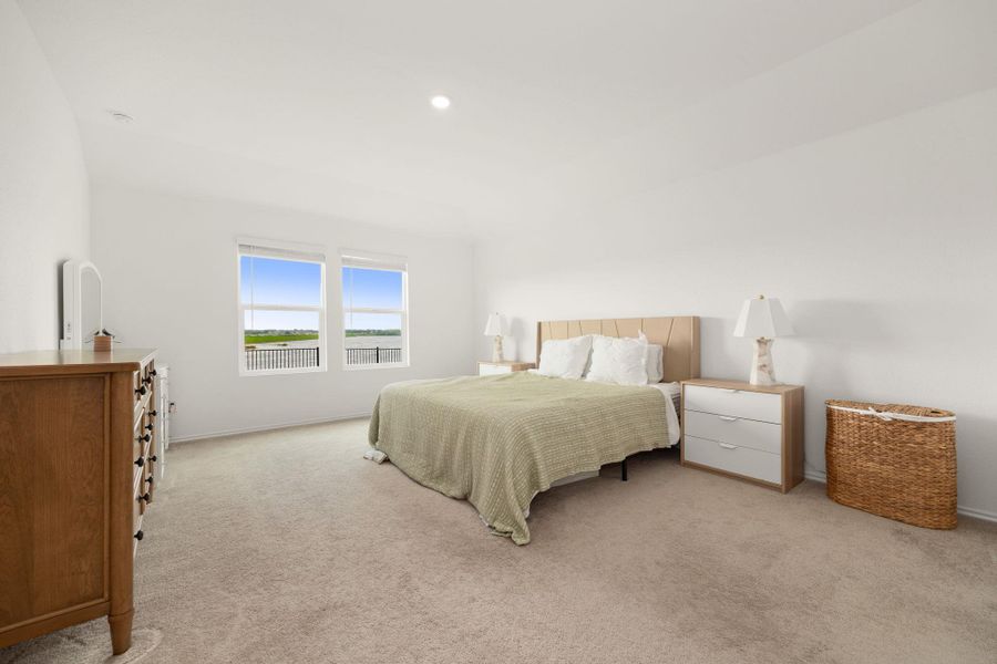 Natural light streams into this serene bedroom, highlighting the plush carpeting and simple, clean design.