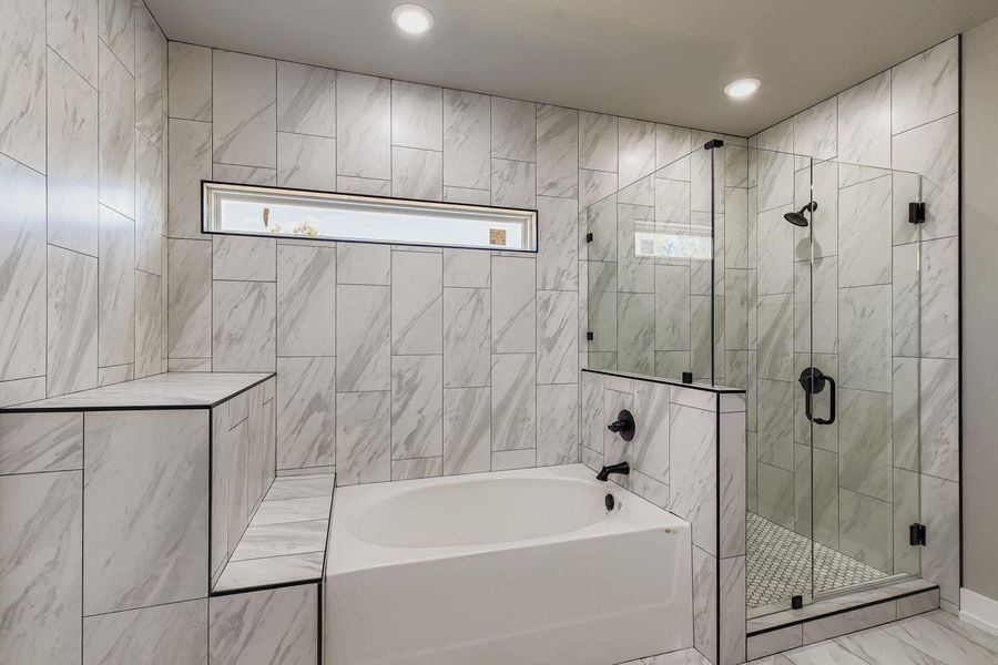 Bathroom featuring a stall shower, a garden tub, marble finish flooring, and tile walls