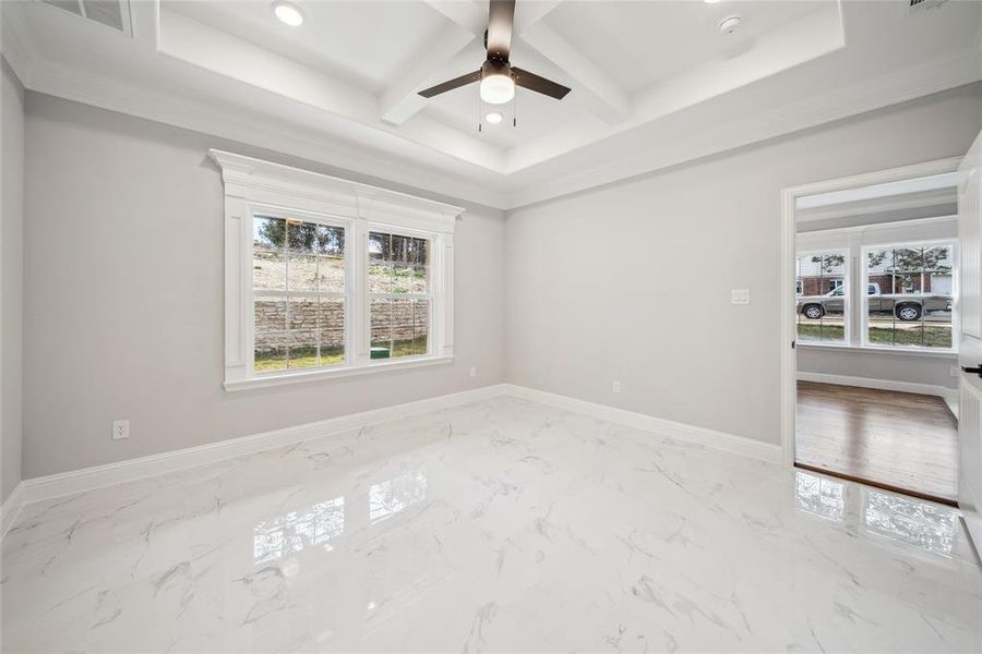Spacious room featuring white marble-look flooring and a tray ceiling with recessed lighting