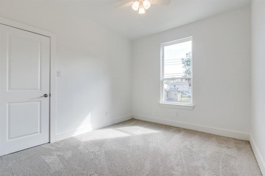 Carpeted empty room featuring ceiling fan