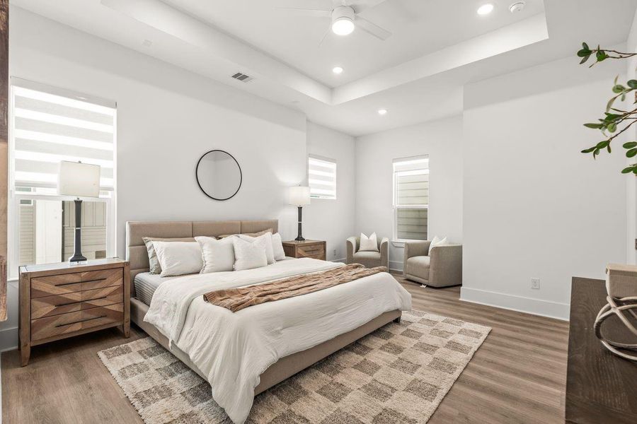 A sense of openness and restraint defines the primary suite, where a thoughtfully positioned seating area introduces an additional layer of comfort and versatility.