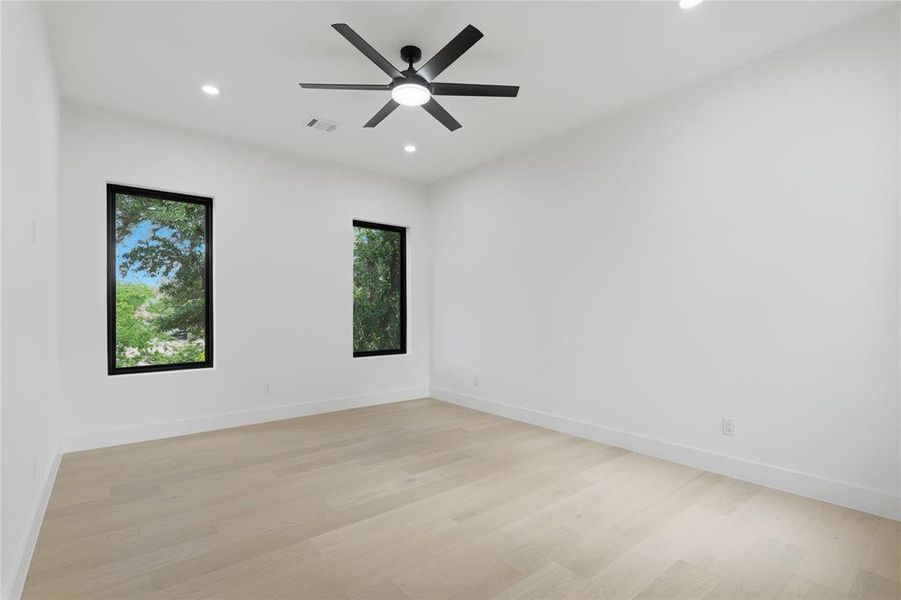 Spacious room featuring light wood-finish flooring, recessed lighting, and a contemporary ceiling fan Spacious room featuring light wood-finish flooring, recessed lighting, and a contemporary ceiling fan