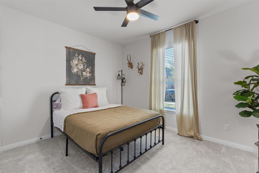 Bedroom with a ceiling fan and light colored carpet