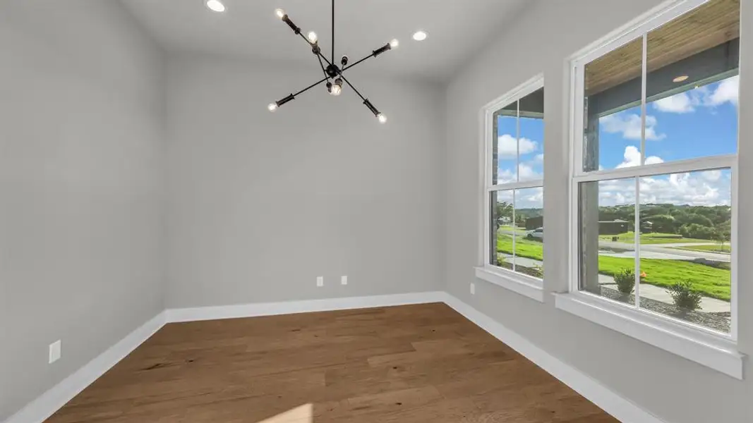 Spacious room featuring wood-finish flooring, light grey walls, and white baseboards Spacious room featuring wood-finish flooring, light grey walls, and white baseboards