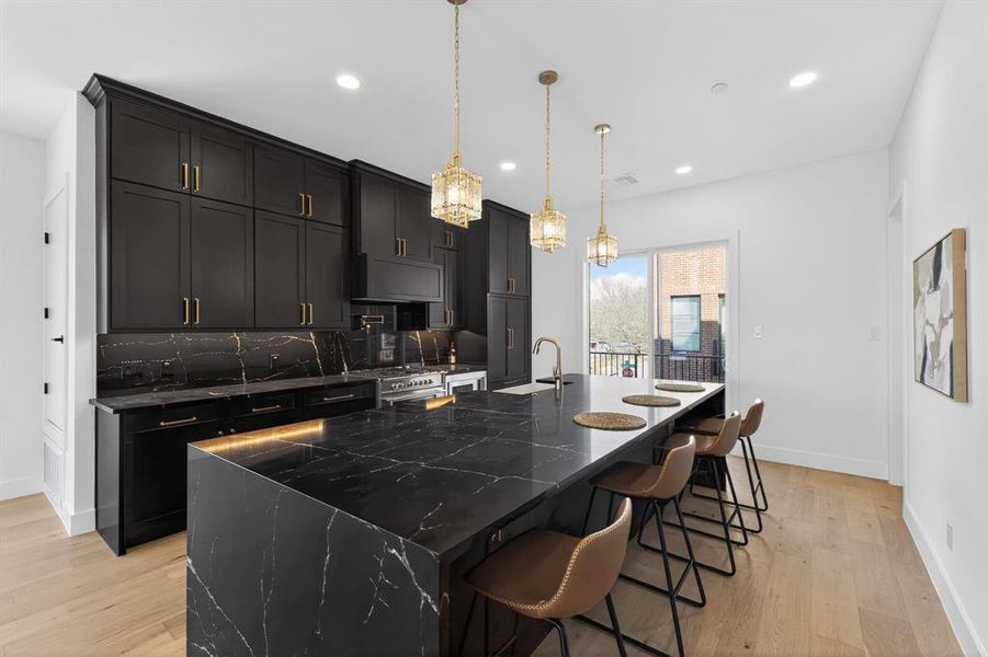 Kitchen featuring dark cabinetry, dark stone counters, a breakfast bar, and a spacious island