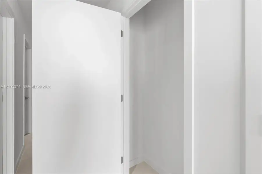 Interior closet featuring a clean, white-painted finish, smooth door paneling, and brushed nickel hardware