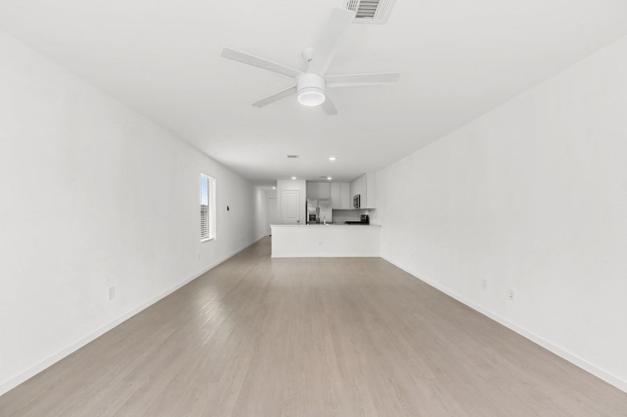 Spacious living room offers a long, open footprint with light-toned flooring, a ceiling fan, and a direct sightline to the kitchen. Spacious living room offers a long, open footprint with light-toned flooring, a ceiling fan, and a direct sightline to the kitchen.