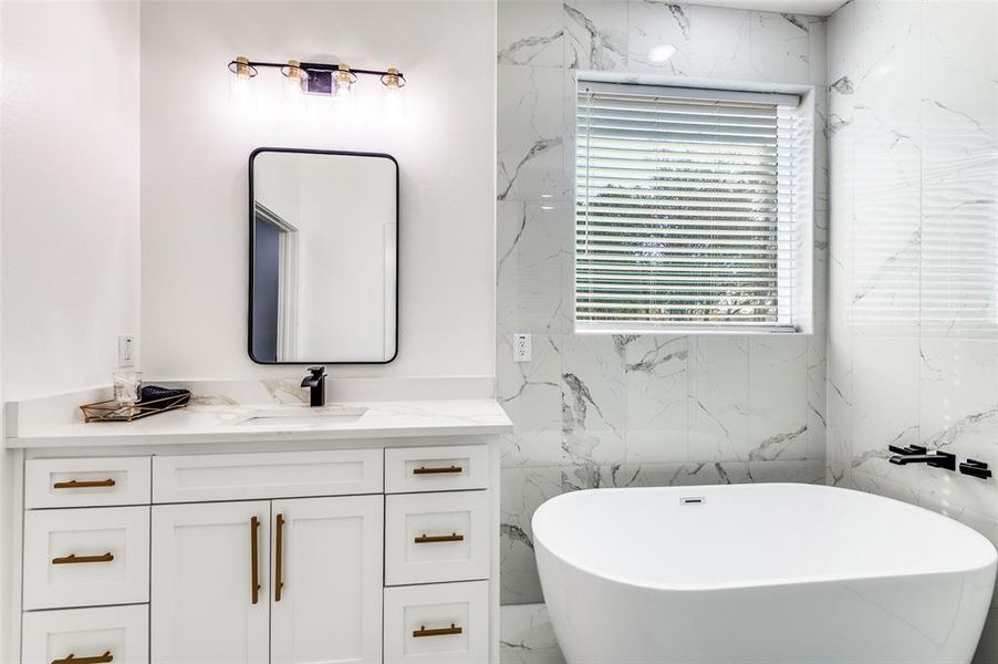 Bathroom with vanity, a soaking tub, and marble tiled floors