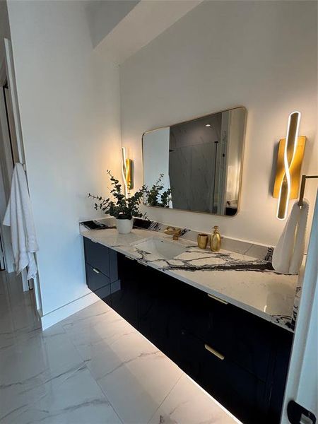 Bathroom featuring light marble finish floors, a marble finish shower, and vanity Bathroom featuring light marble finish floors, a marble finish shower, and vanity