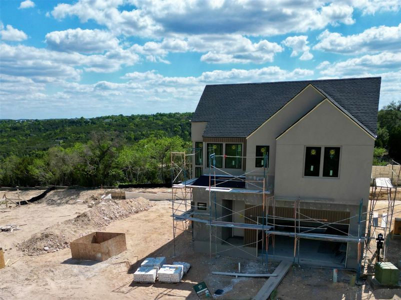 The property features a two-story design with a dark shingled roof and a light-colored stucco exterior