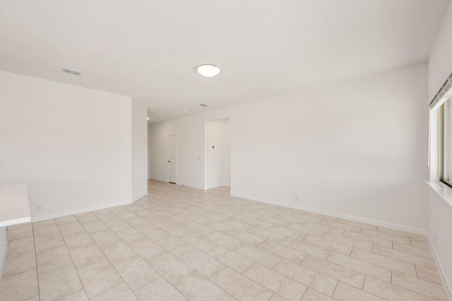 Empty room with white walls, light tile floors, and a window on the right side