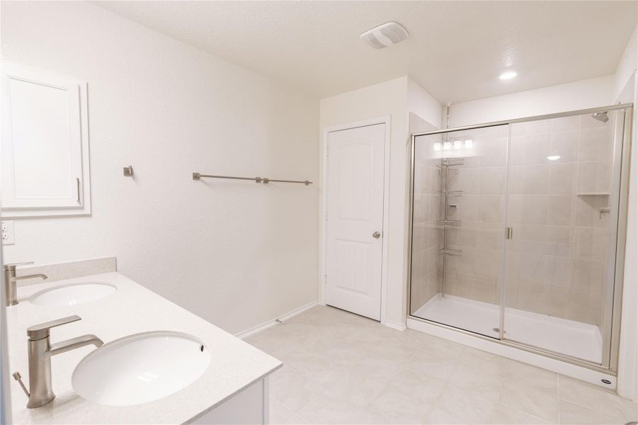 Bright and clean primary bathroom featuring a dual vanity and a spacious glass-enclosed shower. Bright and clean primary bathroom featuring a dual vanity and a spacious glass-enclosed shower.