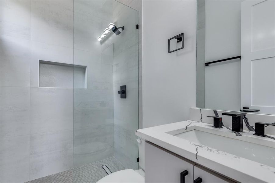 Bathroom featuring toilet, an enclosed shower, and vanity