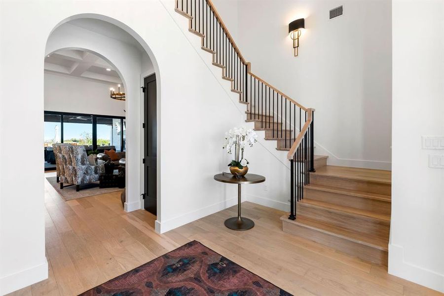 Stairs with coffered ceiling, beam ceiling, wood-type flooring, arched walkways, and a towering ceiling Stairs with coffered ceiling, beam ceiling, wood-type flooring, arched walkways, and a towering ceiling