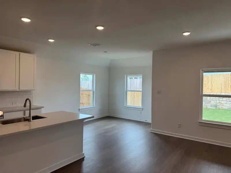 Kitchen featuring dark wood-type flooring, tasteful backsplash, recessed lighting, white cabinetry, and light countertops Kitchen featuring dark wood-type flooring, tasteful backsplash, recessed lighting, white cabinetry, and light countertops