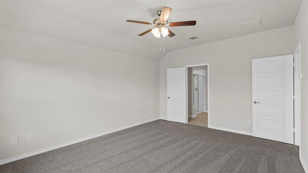 Spacious room featuring vaulted ceilings, a ceiling fan with integrated lighting, and plush grey carpeting