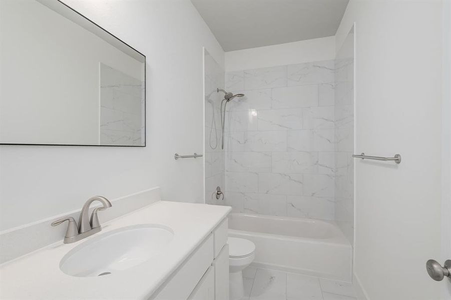 Full bathroom featuring toilet, tiled shower / bath combo, and vanity