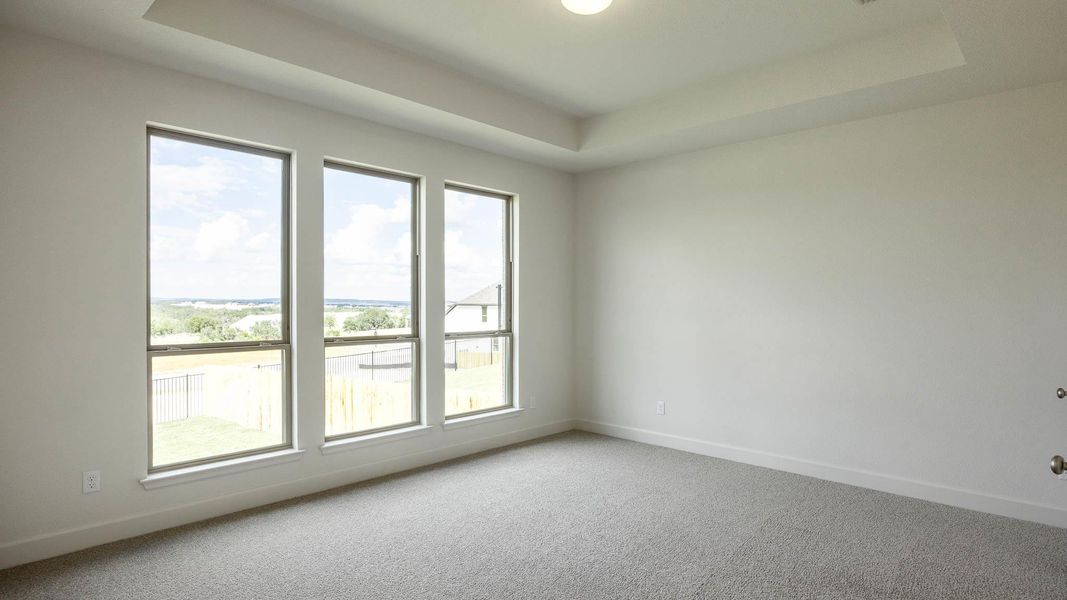 Empty room featuring a raised ceiling and carpet flooring Empty room featuring a raised ceiling and carpet flooring