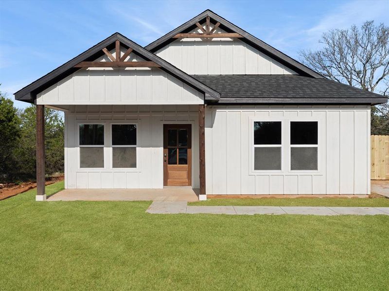 View of front facade with a shingled roof, a front lawn, covered porch, and board and batten siding View of front facade with a shingled roof, a front lawn, covered porch, and board and batten siding
