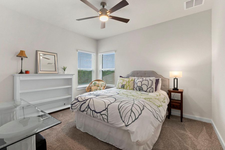 Bedroom featuring two windows with blinds, a ceiling fan with integrated lighting, and carpet flooring
