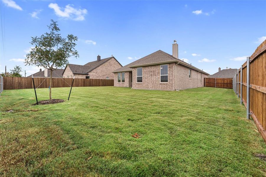 Rear view of property featuring a fenced backyard, a chimney, and brick siding Rear view of property featuring a fenced backyard, a chimney, and brick siding