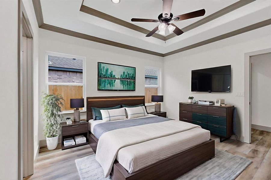 Bedroom featuring a raised ceiling, light wood-type flooring, crown molding, and ceiling fan