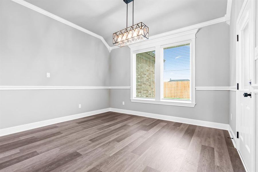 Dining room with dark wood finished floors, a chandelier, baseboards, and ornamental molding Dining room with dark wood finished floors, a chandelier, baseboards, and ornamental molding