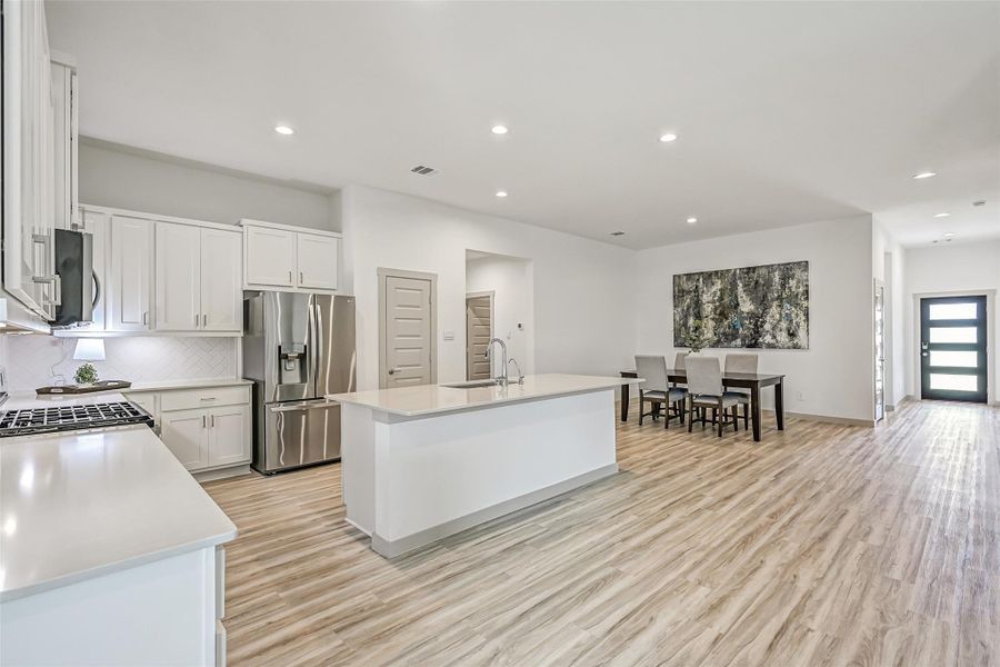 The heart of the home is an impressive open-concept kitchen & dining space with an oversized island, abundant cabinetry, stainless appliances and continuous wood-look flooring that creates a seamless flow throughout the main living areas. The heart of the home is an impressive open-concept kitchen & dining space with an oversized island, abundant cabinetry, stainless appliances and continuous wood-look flooring that creates a seamless flow throughout the main living areas.