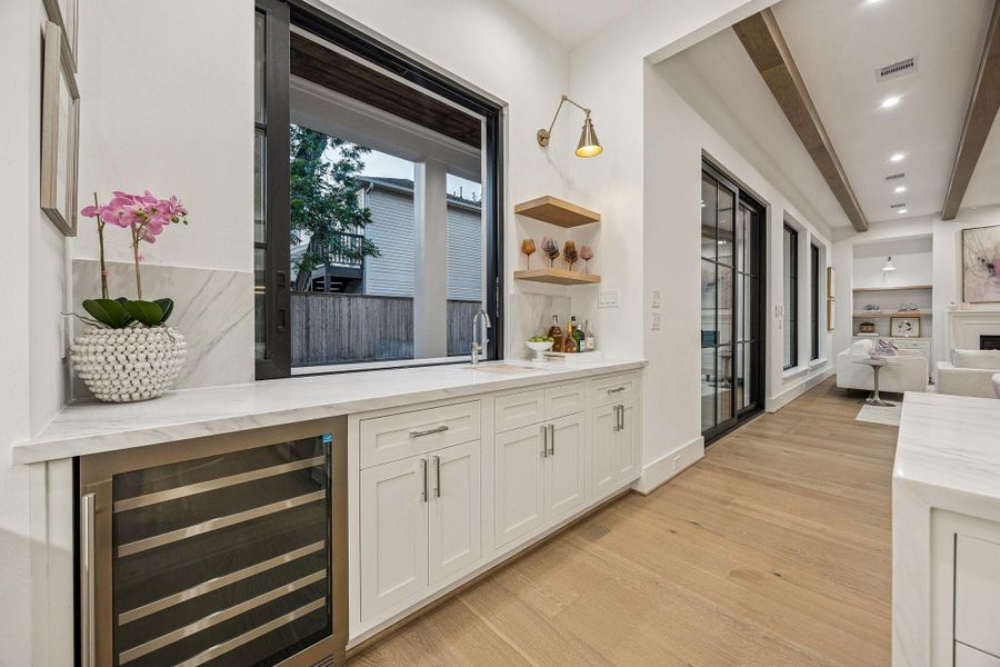 Fantastic Wet-Bar with a Sliding Glass Window! Pass drinks and food back and forth to the outside Bar/Grill Area. There are Inset Soft-Close Shaker Style Cabinets/Drawers with a Slab Quartz Counter and Backsplash, Kraus 17" Undermount Single Basin Stainless Steel Sink with Brizo Bar Faucet, White Oak Floating Shelves with a Natural Stain, Iron Swing Arm Sconce in a Brass Gold Finish. There is also a Zephyr Dual Zone Wine Cooler. Fantastic Wet-Bar with a Sliding Glass Window! Pass drinks and food back and forth to the outside Bar/Grill Area. There are Inset Soft-Close Shaker Style Cabinets/Drawers with a Slab Quartz Counter and Backsplash, Kraus 17" Undermount Single Basin Stainless Steel Sink with Brizo Bar Faucet, White Oak Floating Shelves with a Natural Stain, Iron Swing Arm Sconce in a Brass Gold Finish. There is also a Zephyr Dual Zone Wine Cooler.