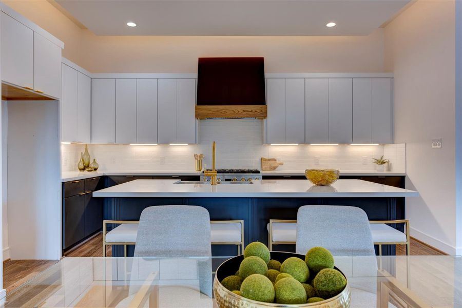 Bright under-cabinet lighting highlights the clean white finishes and durable quartz countertops, creating a modern and inviting kitchen space.