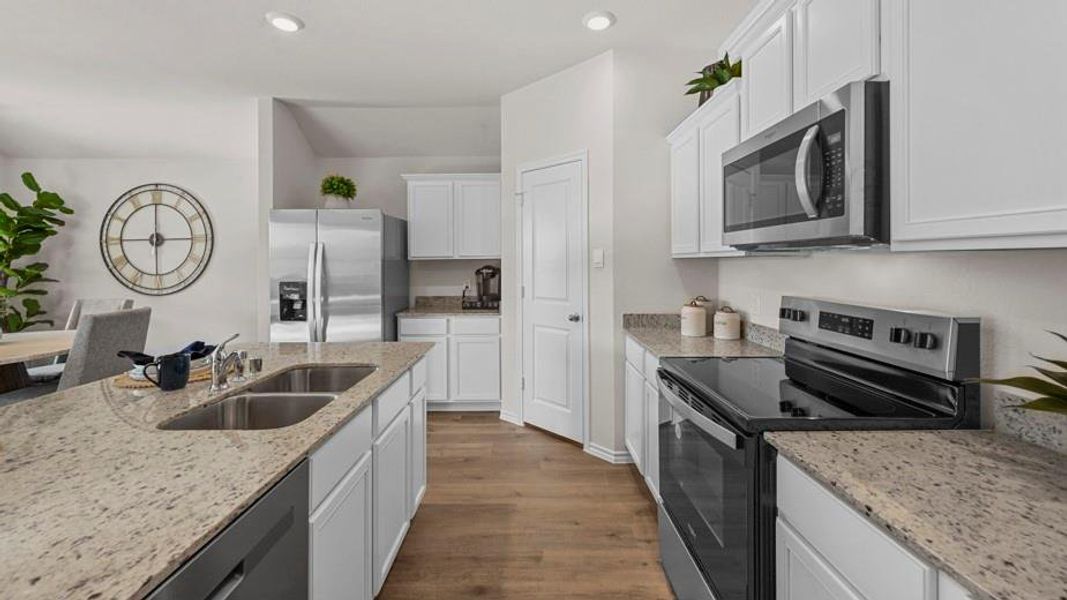 Kitchen with stainless steel appliances, white cabinetry, dark wood-style flooring, light stone counters, and recessed lighting