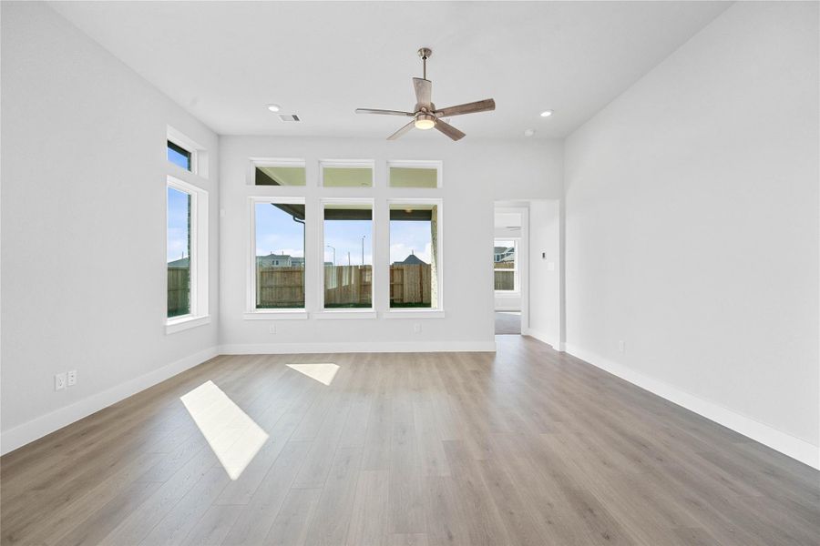 A grand great room with tall ceilings, ceiling fan, abundant natural light, and an open, inviting ambiance--perfect for gatherings, relaxation, and making memories.